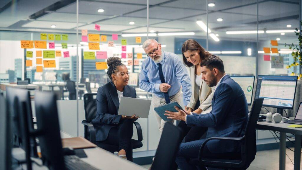 Team of working professionals in an office looking at a tablet