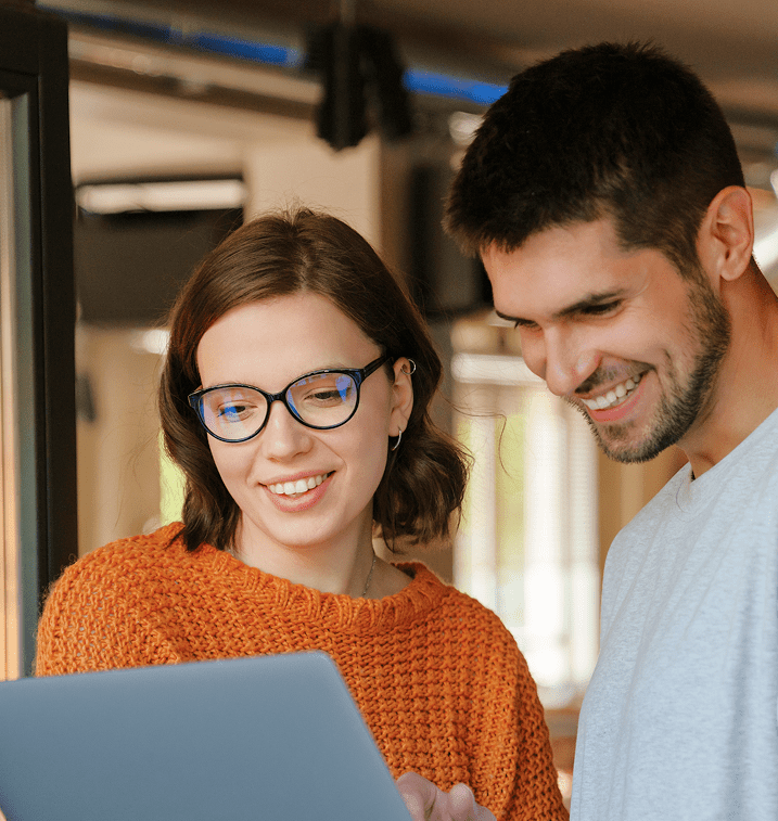 Male and female professionals smiling at a laptop